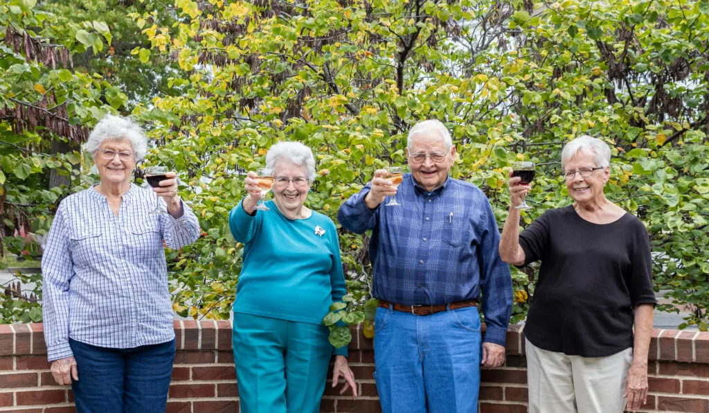Four retirees raising wine glasses to their independent living lifestyle