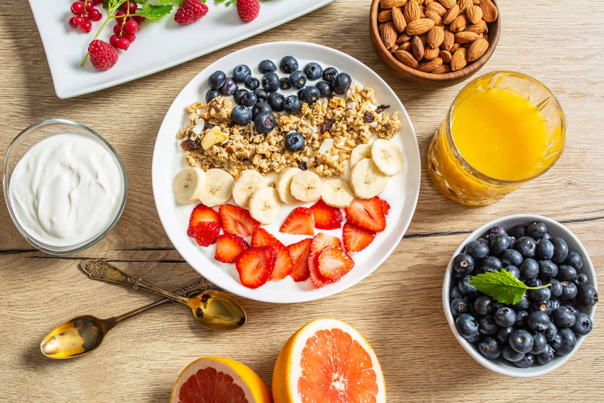 a table full of healthy snacks for older adults including berries, yogurt, nuts and juice 