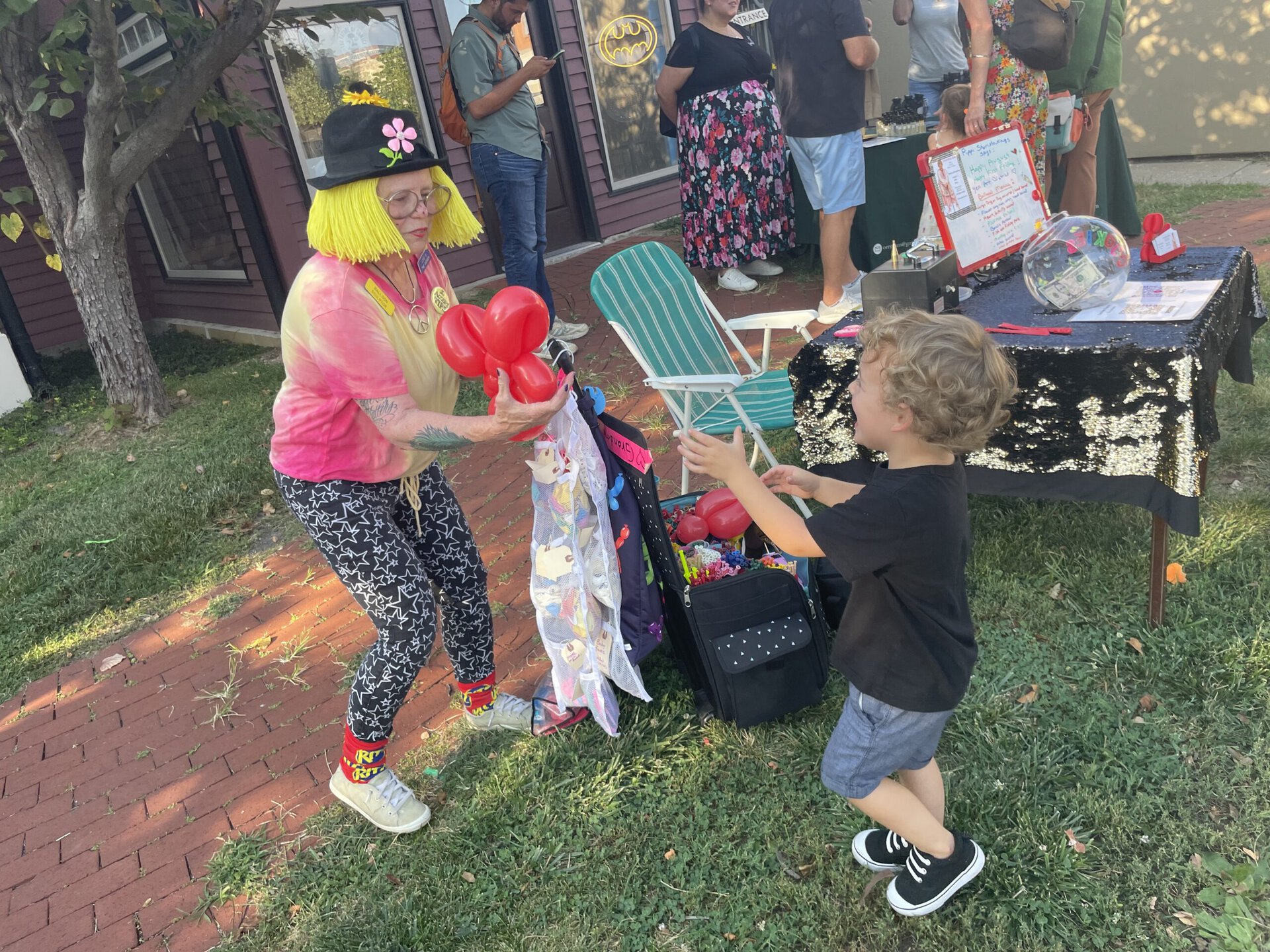 a lady making a red balloon animal for a little boy