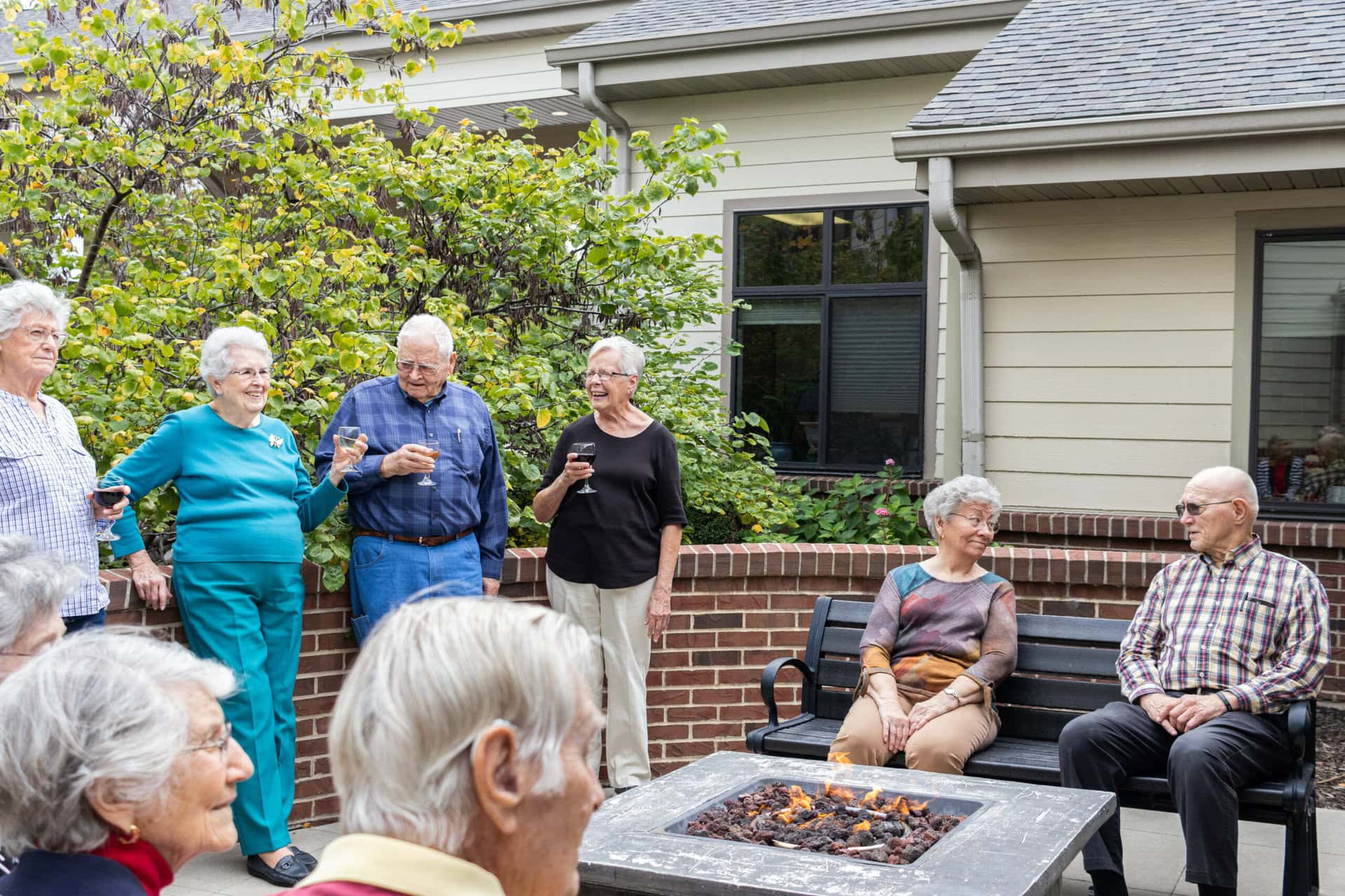 a group of seniors talking, sipping wine around the firepit