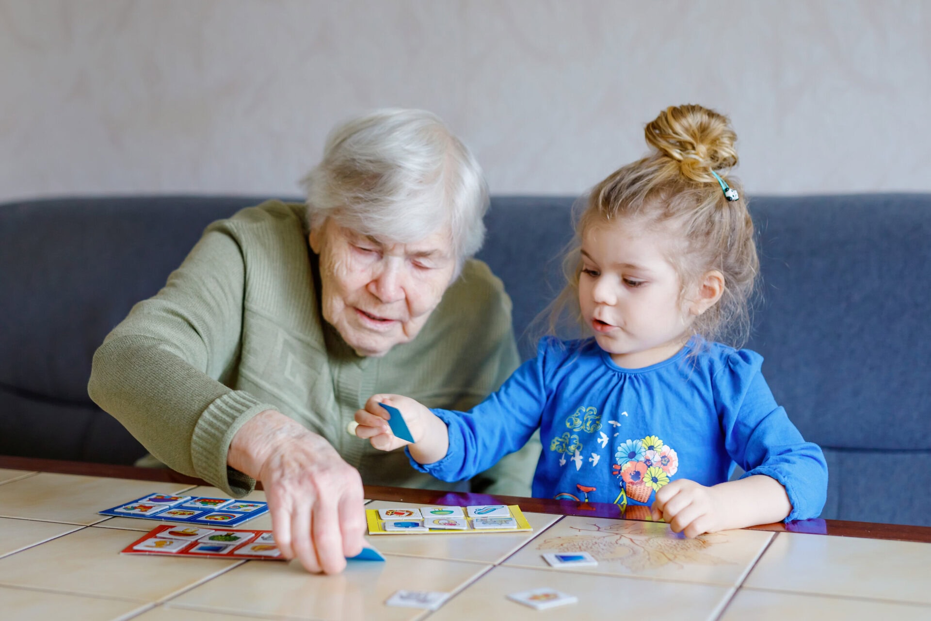 Beautiful toddler girl and grand grandmother playing together pictures lotto table cards game